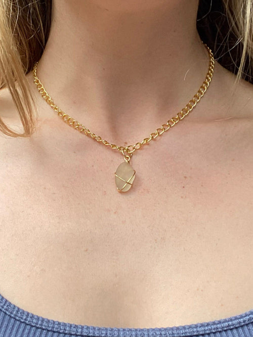 Person wearing a blue tank top and gold necklace with a pendant.